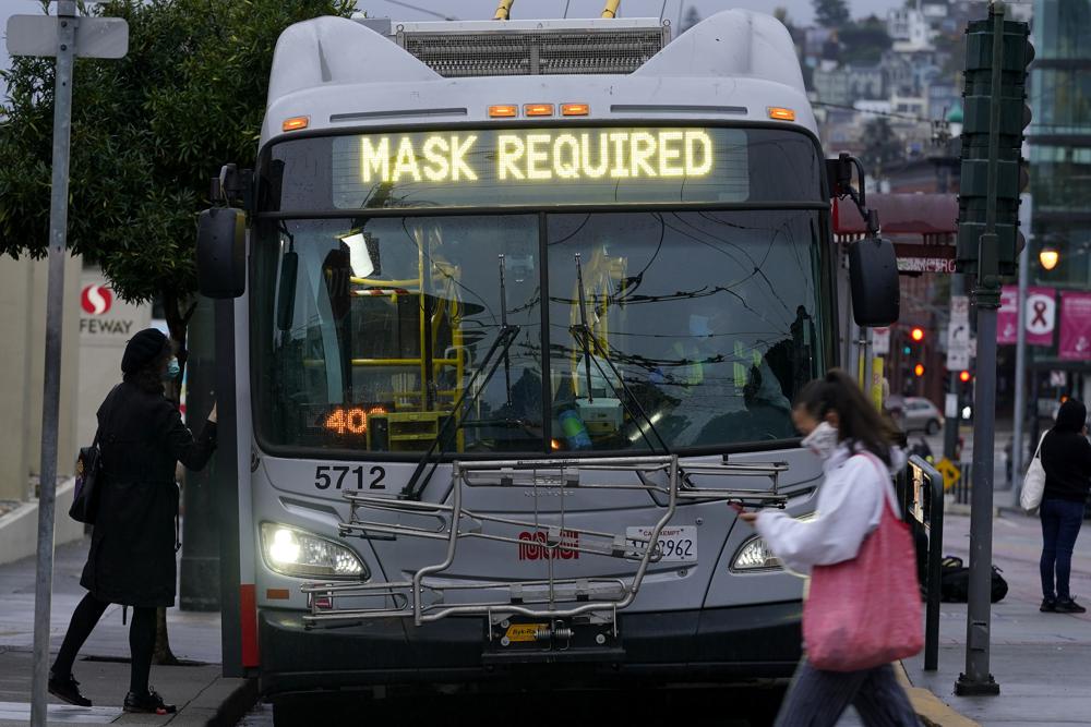 In this Tuesday, Nov. 17, 2020 file photo, a sign on a Muni bus in San Francisco advises that passengers are required to wear masks, during the coronavirus pandemic.