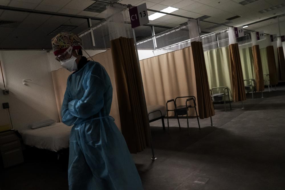 In this Wednesday, Feb. 10, 2021 file photo, traveling registered nurse Patricia Carrete, of El Paso, Texas, walks down the hallways during a night shift at a field hospital set up to handle a surge of COVID-19 patients in Cranston, R.I.