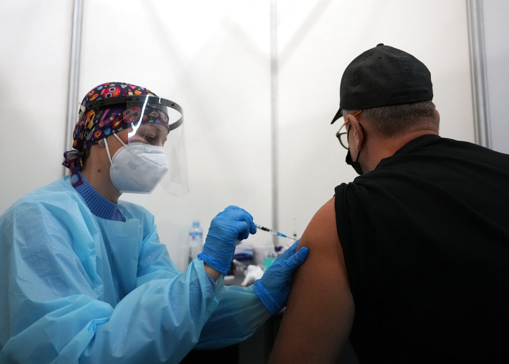 A medical worker administers a shot of Pfizer COVID-19 vaccine to Vitaly Pavlov from Rostov-on-Don at Belgrade Fair makeshift vaccination center in Belgrade, Serbia, Saturday, Oct. 2, 2021. Pavlov looked for a vaccine that would allow his family to travel freely — a quest that brought them to Serbia, where hundreds of Russian citizens have flocked in recent weeks to receive Western-approved COVID-19 shots.