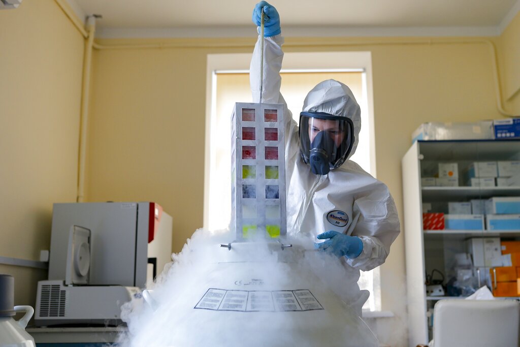 In this Aug. 6, 2020, file photo provided by Russian Direct Investment Fund, an employee works with a coronavirus vaccine at the Nikolai Gamaleya National Center of Epidemiology and Microbiology in Moscow, Russia. Russians are flocking to Serbia to receive Western-approved COVID-19 shots. Although Russia has its own vaccine known as Sputnik V, the shot has not been approved by international health authorities.