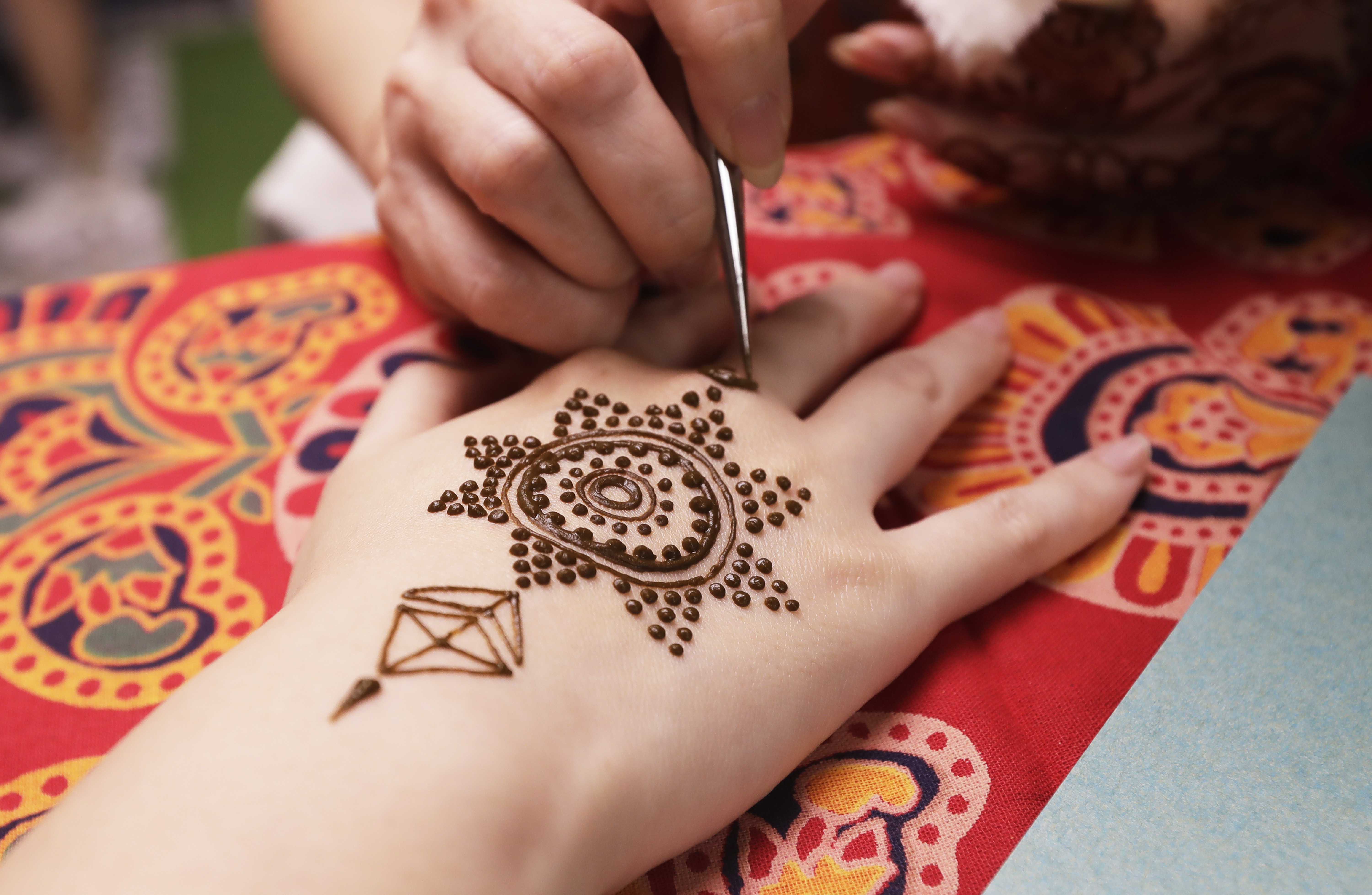 An artist applies henna on the hand of a woman during Diwali