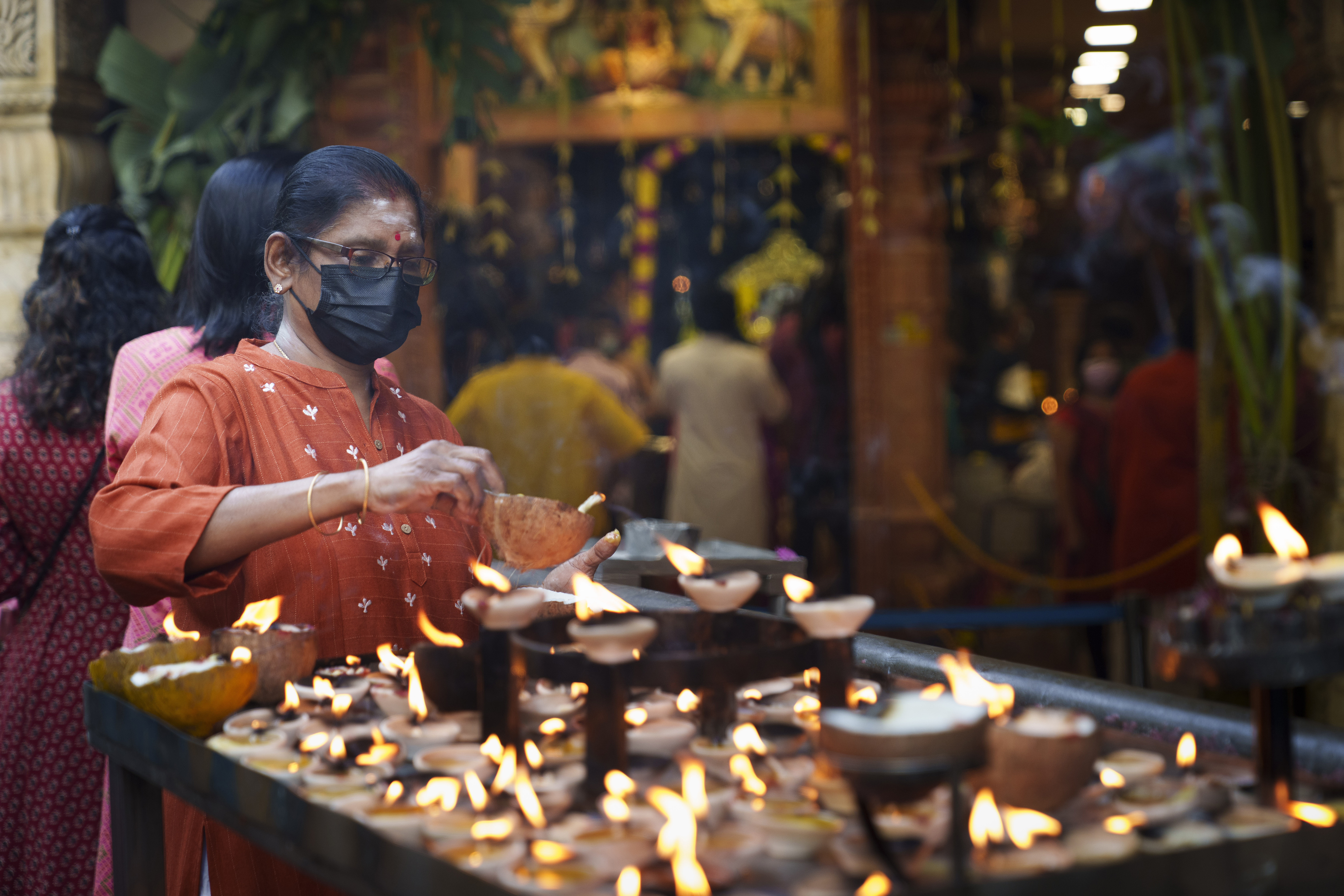 Hindu devotees light clay oil lamps while praying at a temple