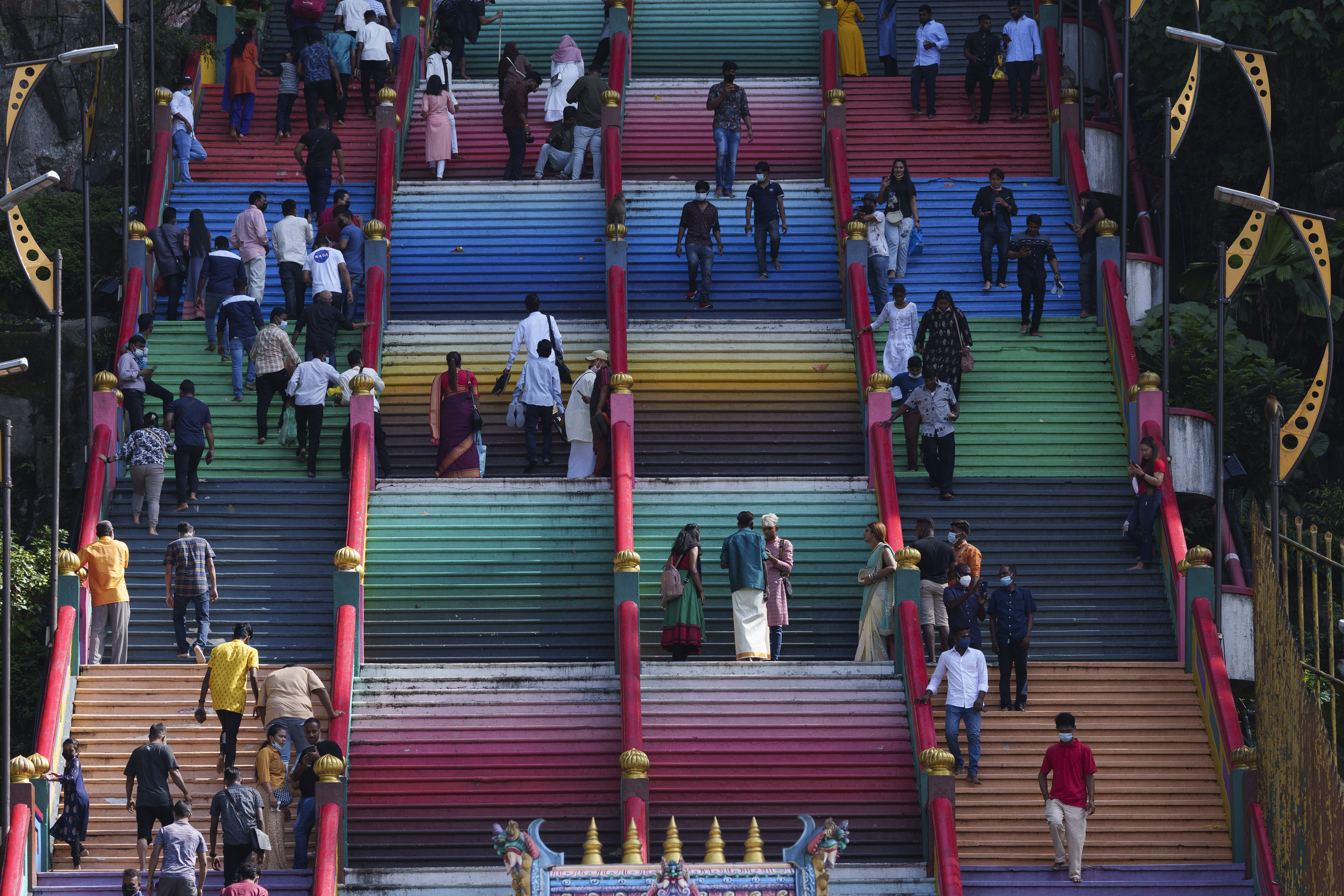 Hindu devotees climb the colored stairs to pray at the Batu Caves temple