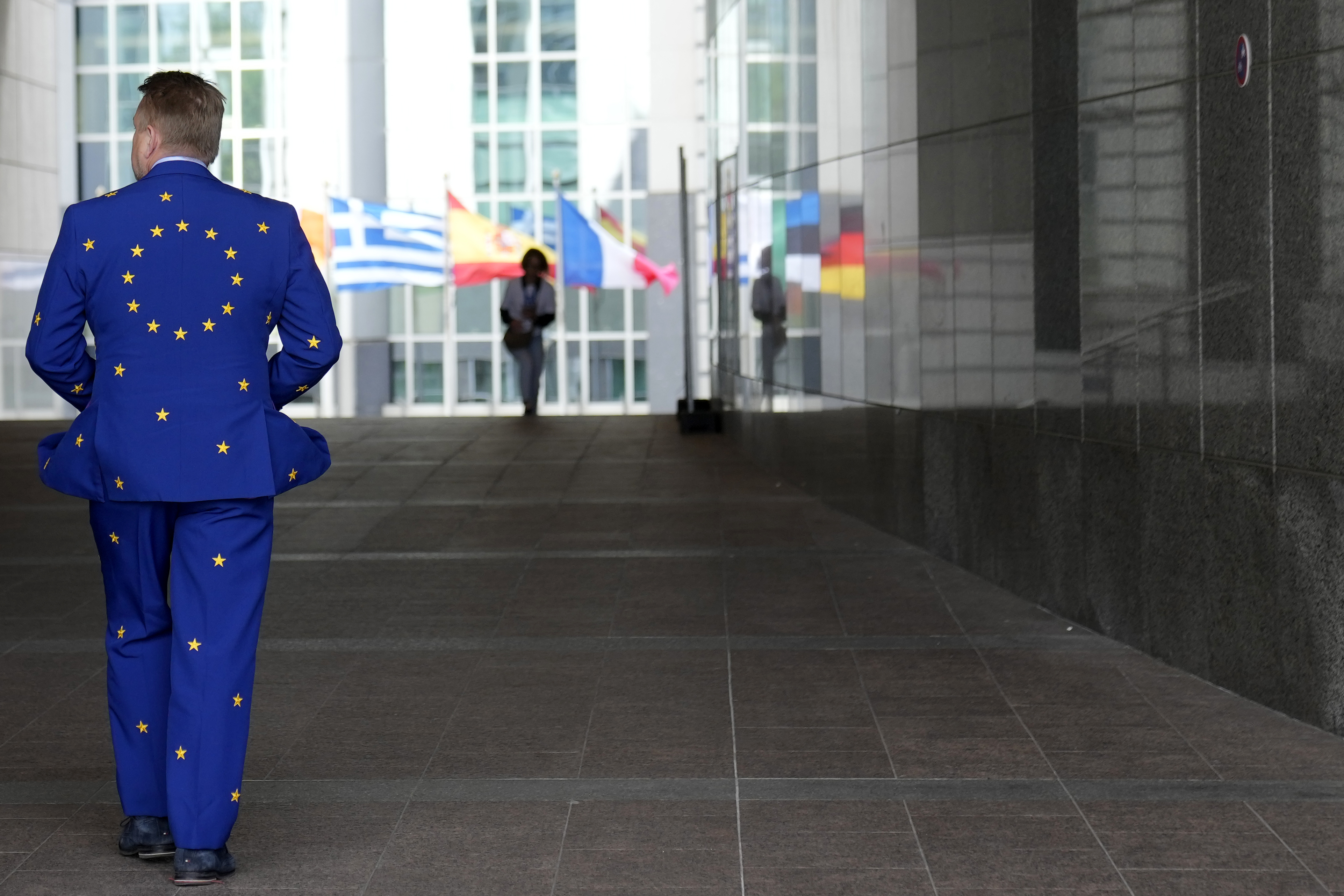 A man wears a suit in the EU colors as he walks outside the European Parliament in Brussels