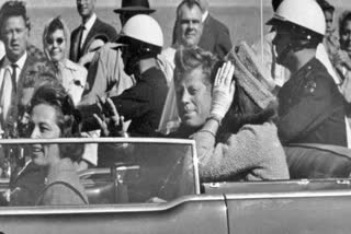 President John F. Kennedy waves from his car in a motorcade approximately one minute before he was shot, Nov. 22, 1963, in Dallas.