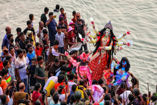 Bangladeshi Hindu devotees immerse an idol of their deity Durga into the Buriganga river in Dhaka on October 13, 2024, during celebrations on the last day of Durga Puja festival.