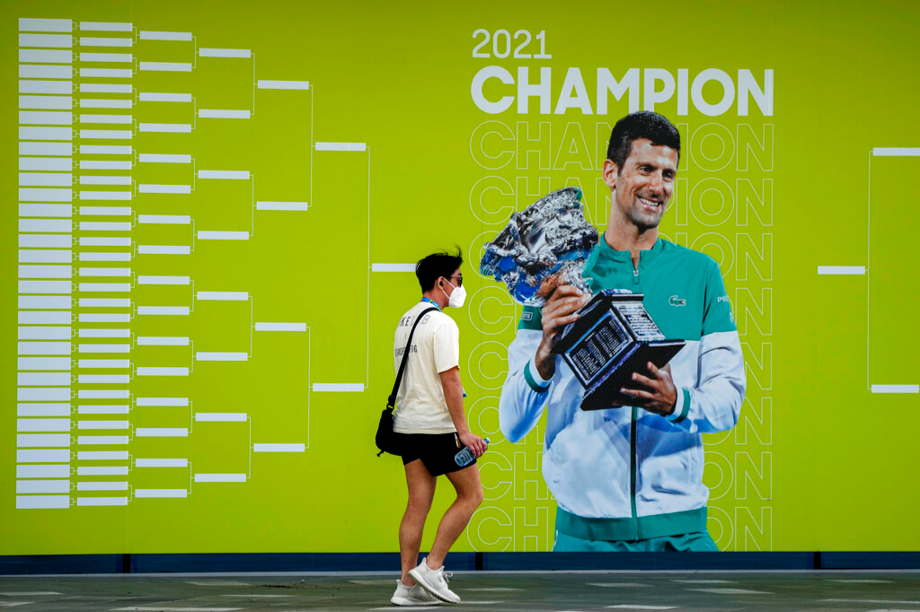 A man walks past a billboard featuring defending champion, Serbia's Novak Djokovic, ahead of the Australian Open at Melbourne Park in Melbourne