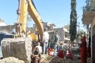 Villagers lay down in front of JCB