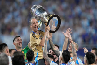 Argentina's staff member Mario De Stefano holds up the trophy as he celebrates with players after defeating Colombia in the Copa America final soccer match in Miami Gardens, Fla., Monday, July 15, 2024.