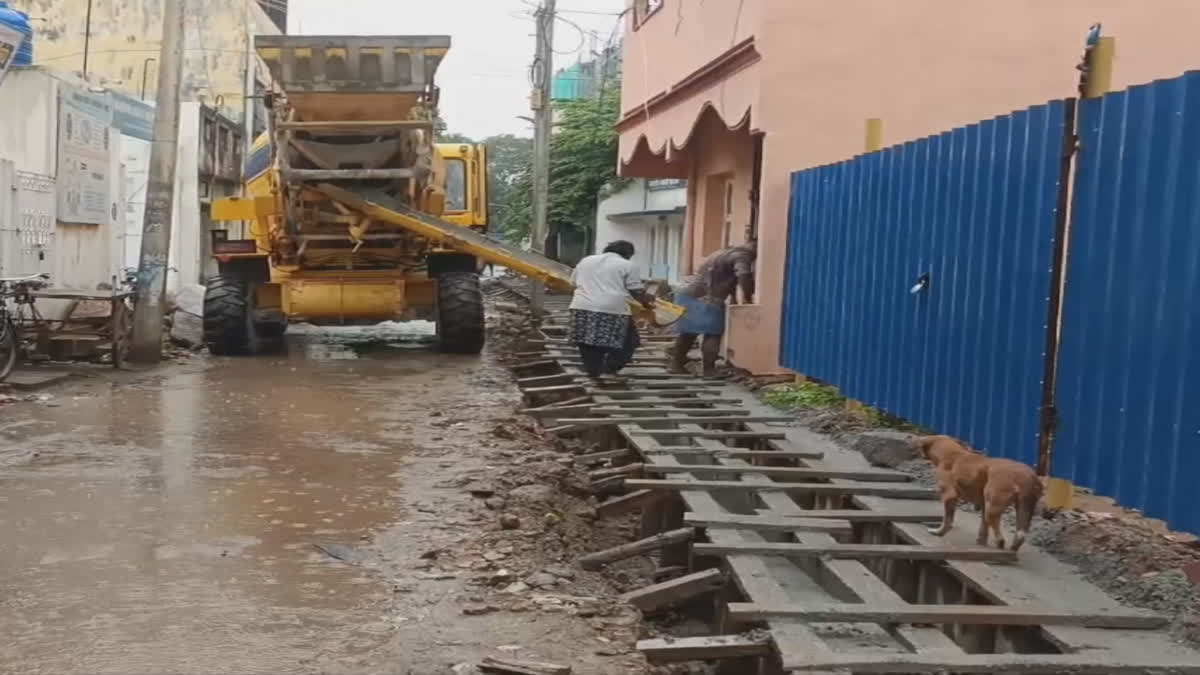 மழைக்கு நடுவே கால்வாய் அமைக்கும் பணியில் ஈடுபட்டு வரும் ஊழியர்கள்