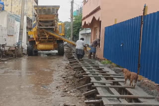 மழைக்கு நடுவே கால்வாய் அமைக்கும் பணியில் ஈடுபட்டு வரும் ஊழியர்கள்