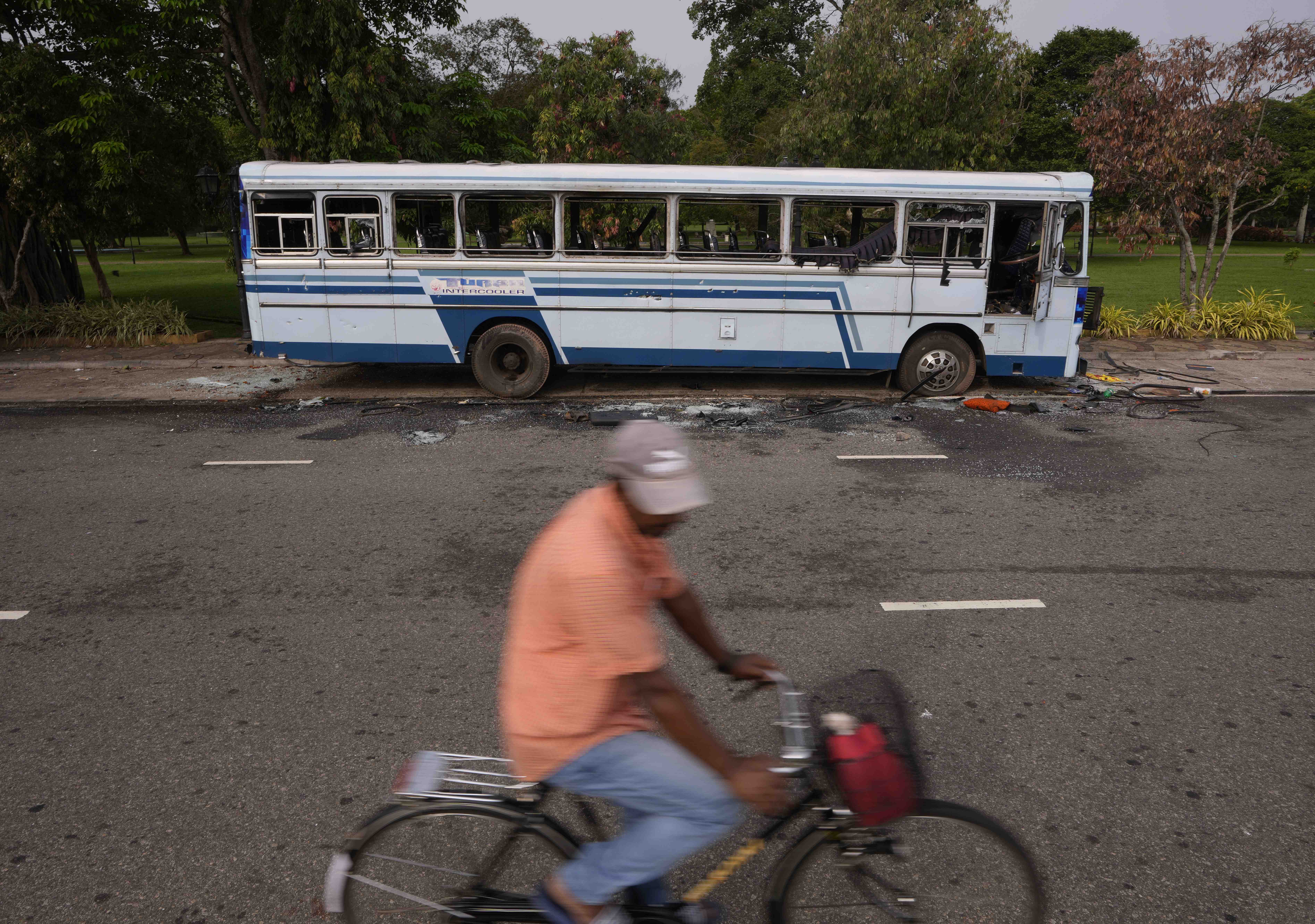 A Sri Lankan man rides past a burnt bus, a day after clashes between government supporters and anti-government protesters in Colombo.