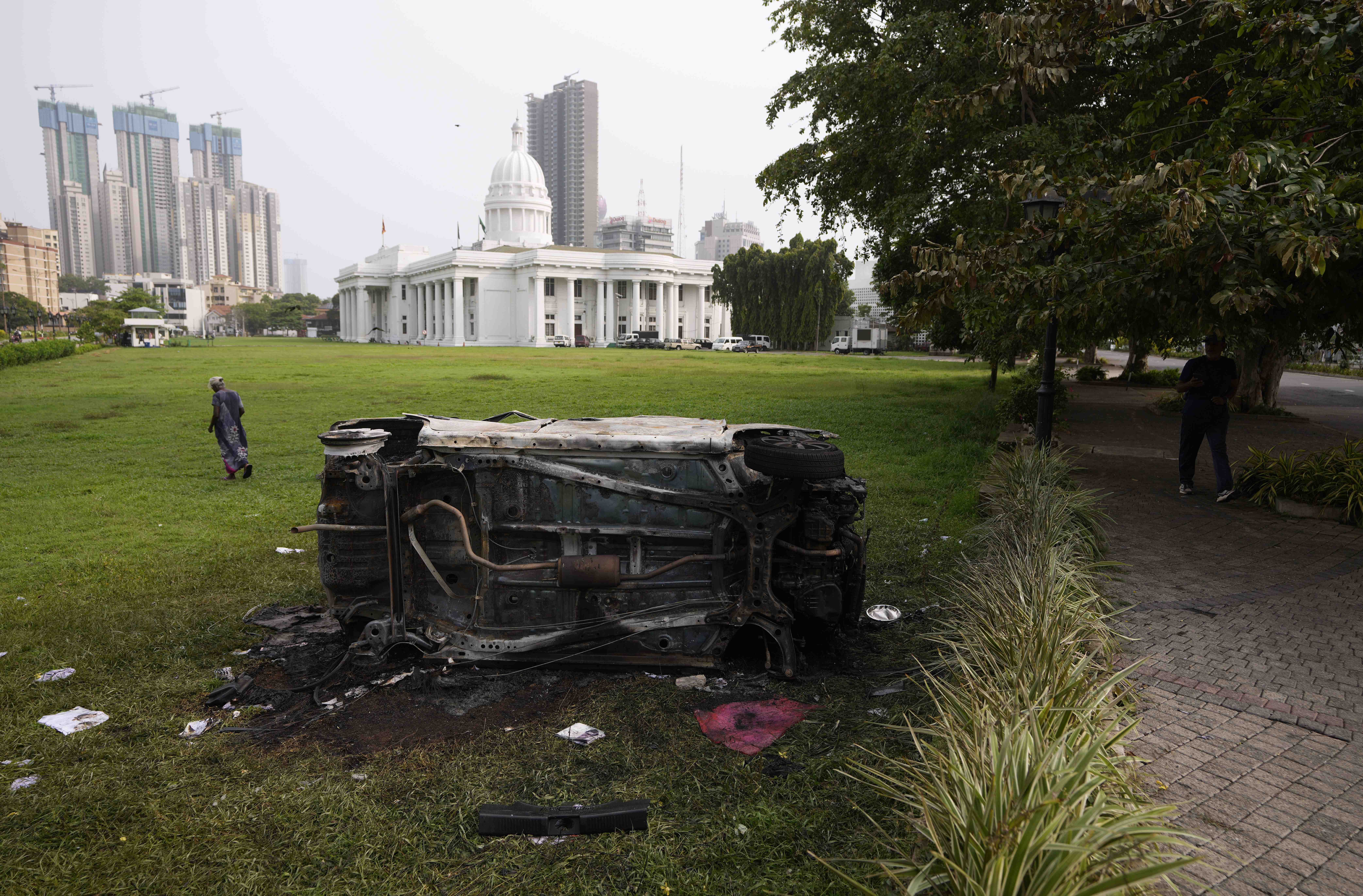 A burnt car lies in the lawns of the Town Hall, a day after the clashes between government supporters and anti government protesters in Colombo on Tuesday.