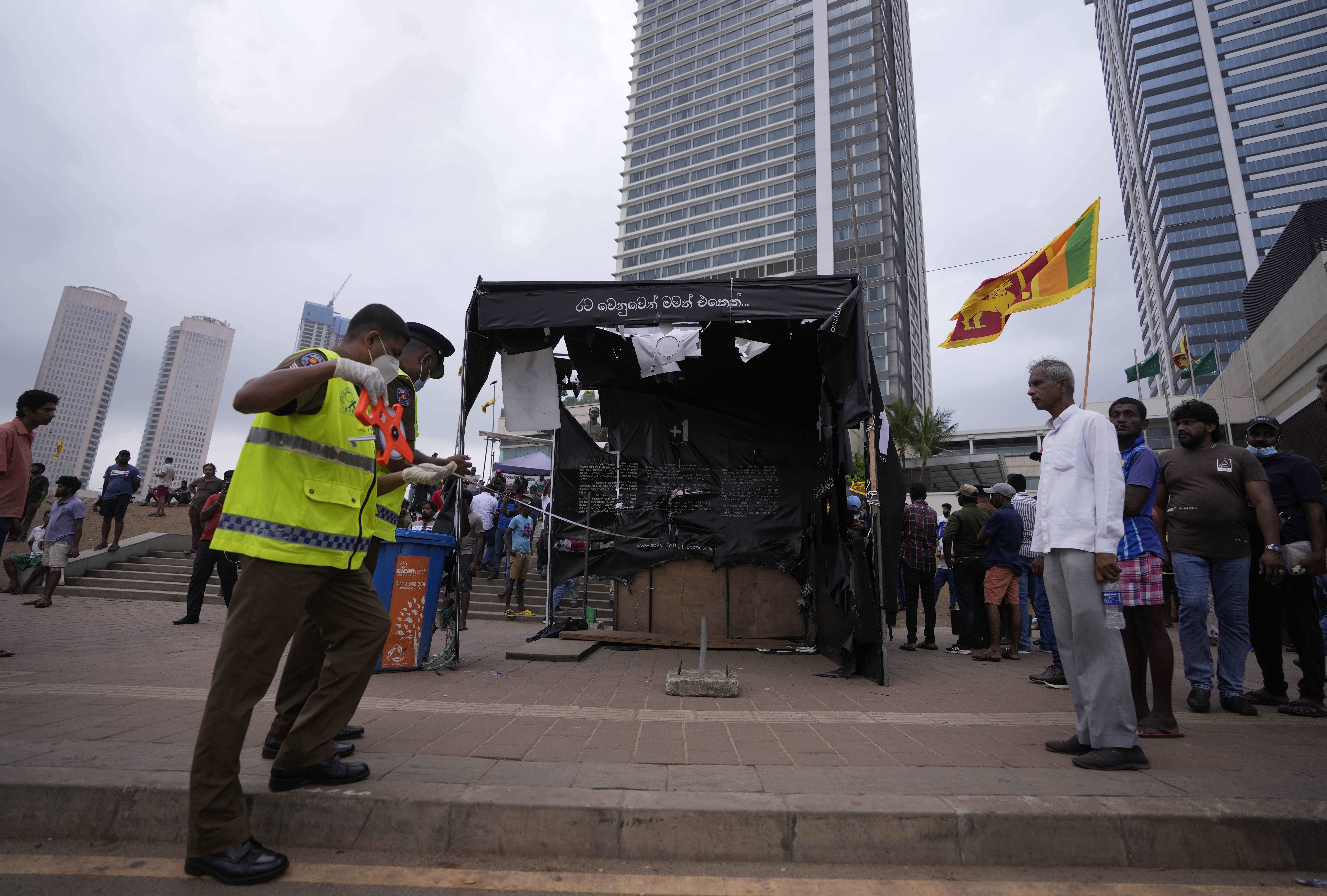 Police officers conduct investigations into aftermath of clashes between government supporters and anti government protesters in Colombo.