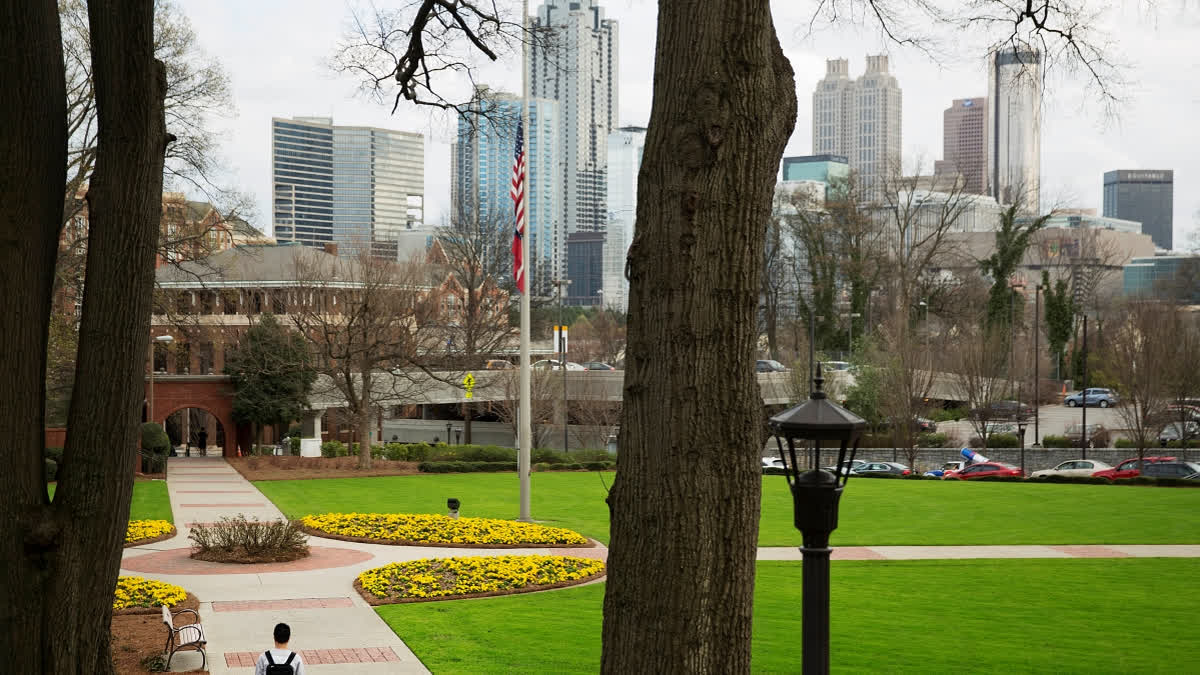FILE - A person walks through the Georgia Tech campus with the downtown skyline in the background, March 11, 2016, in Atlanta.