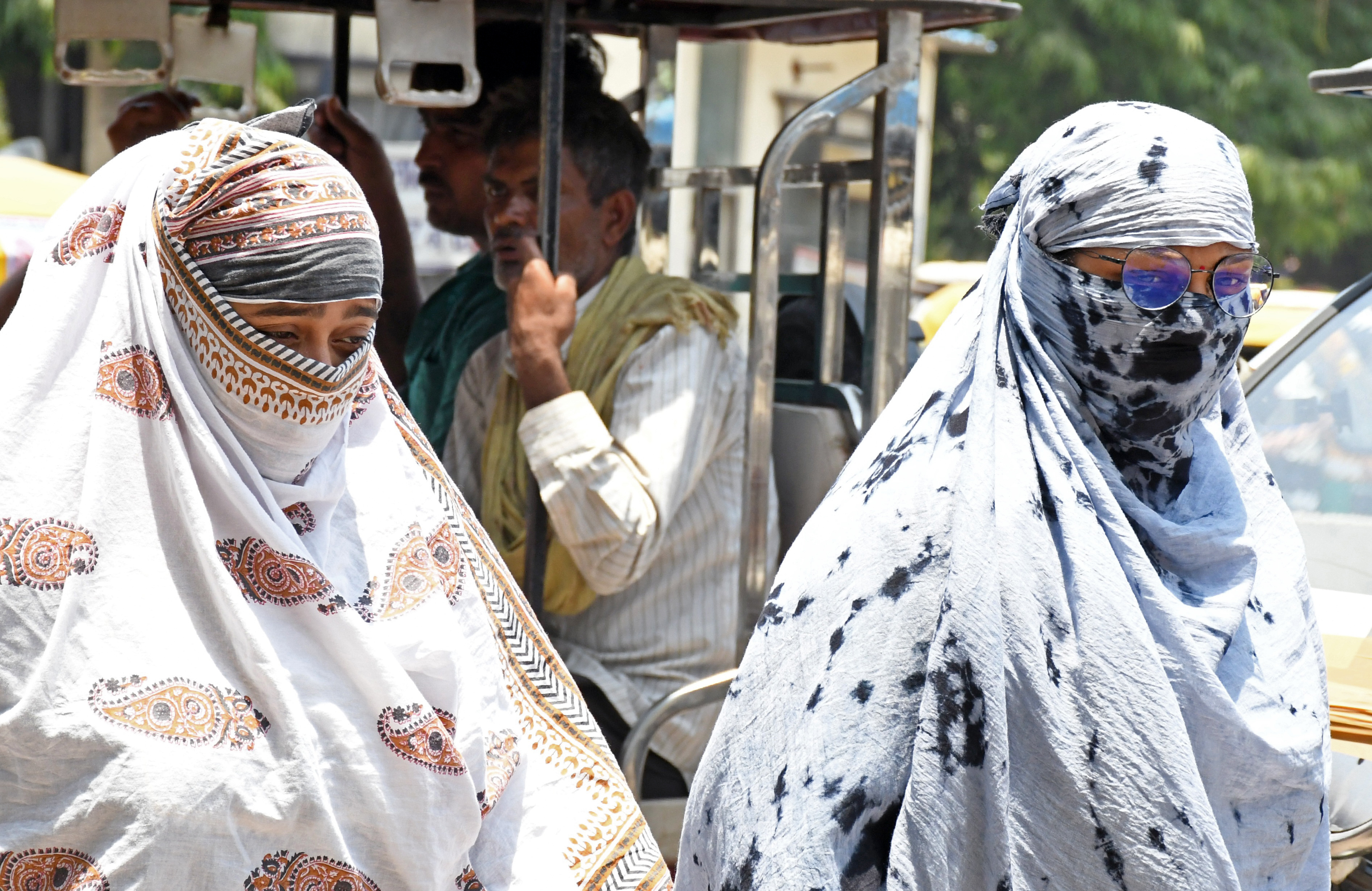 Women cover their faces with scarves to protect themselves from the scorching sun on a hot summer day, in Kanpur, Uttar Pradesh