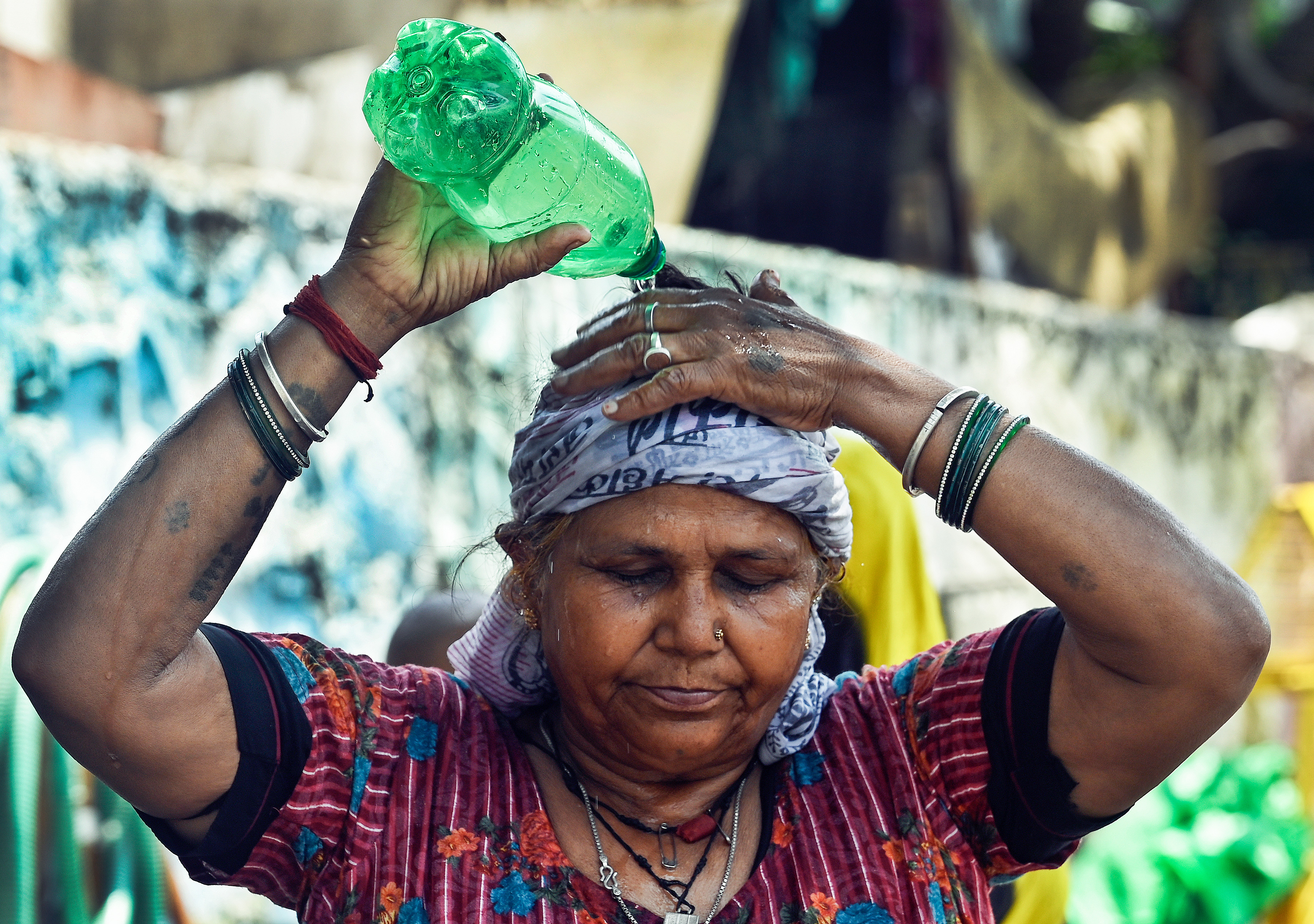 A woman pours water on her head to cool herself amid the ongoing heatwave, at the Swami Vivekananda Camp Chanakyapuri in New Delhi