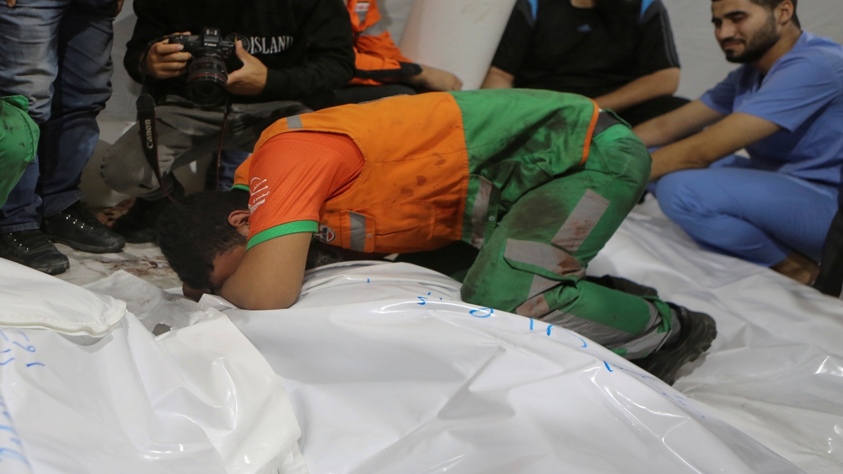 Palestinian civil defense officers mourn over the body of one of their colleagues who arrived dead at the Shifa hospital, after Israeli airstrikes targeted a civil defense site in Gaza City, central Gaza Strip, early Monday, Oct. 16, 2023. (AP Photo/Abed Khaled)