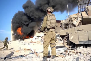 In this image taken from a video released by the Israeli Defense Forces on Tuesday, Nov. 14, 2023, an Israeli soldier holds a weapon in Gaza City. The Israeli military released footage on Tuesday that it said shows joint operational activity of two army brigades in its advancement on the ground in Gaza Strip. (Israel Defense Forces via AP)