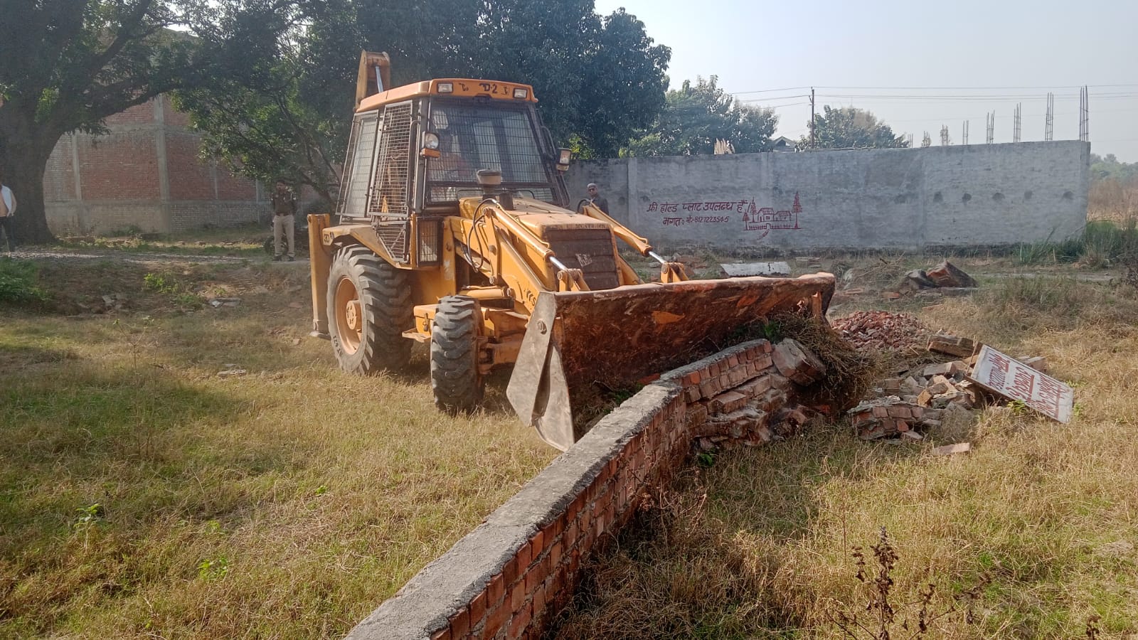 बाउंड्रीवाॅल को ध्वस्त करती जेसीबी.