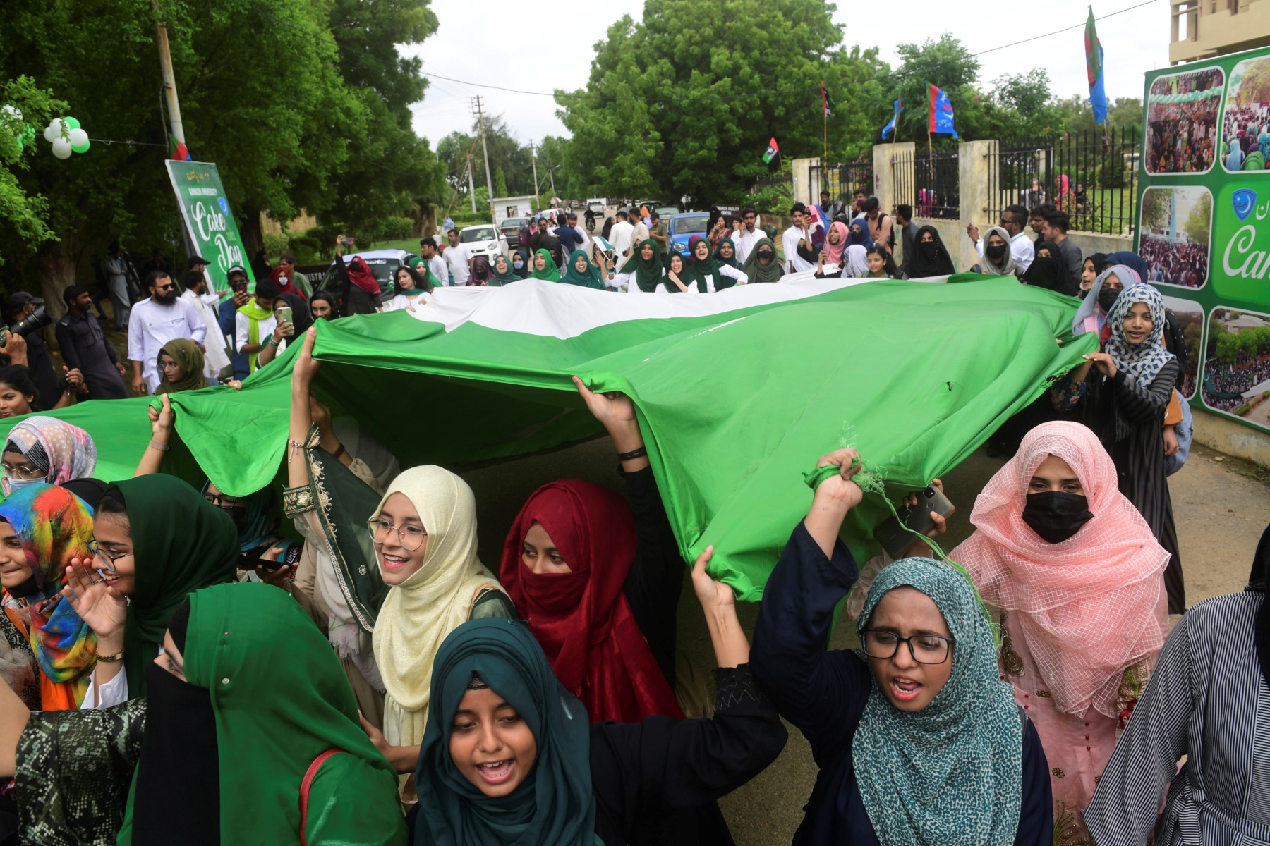 کراچی میں پاکستان کے 75 ویں یوم آزادی کا جشن مناتے ہوئے طلباء مارچ کے دوران پاکستان کا ایک بڑا جھنڈا اٹھائے ہوئے