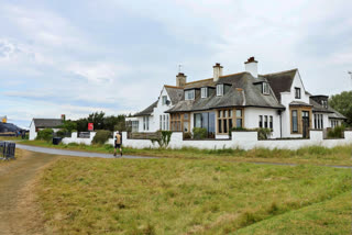 Spectators walk past "Blackrock house" that is listed for sale near the second and 16th holes at Royal Troon golf club, venue for the British Open Golf Championships, in Troon, Scotland, Tuesday, July 16, 2024.