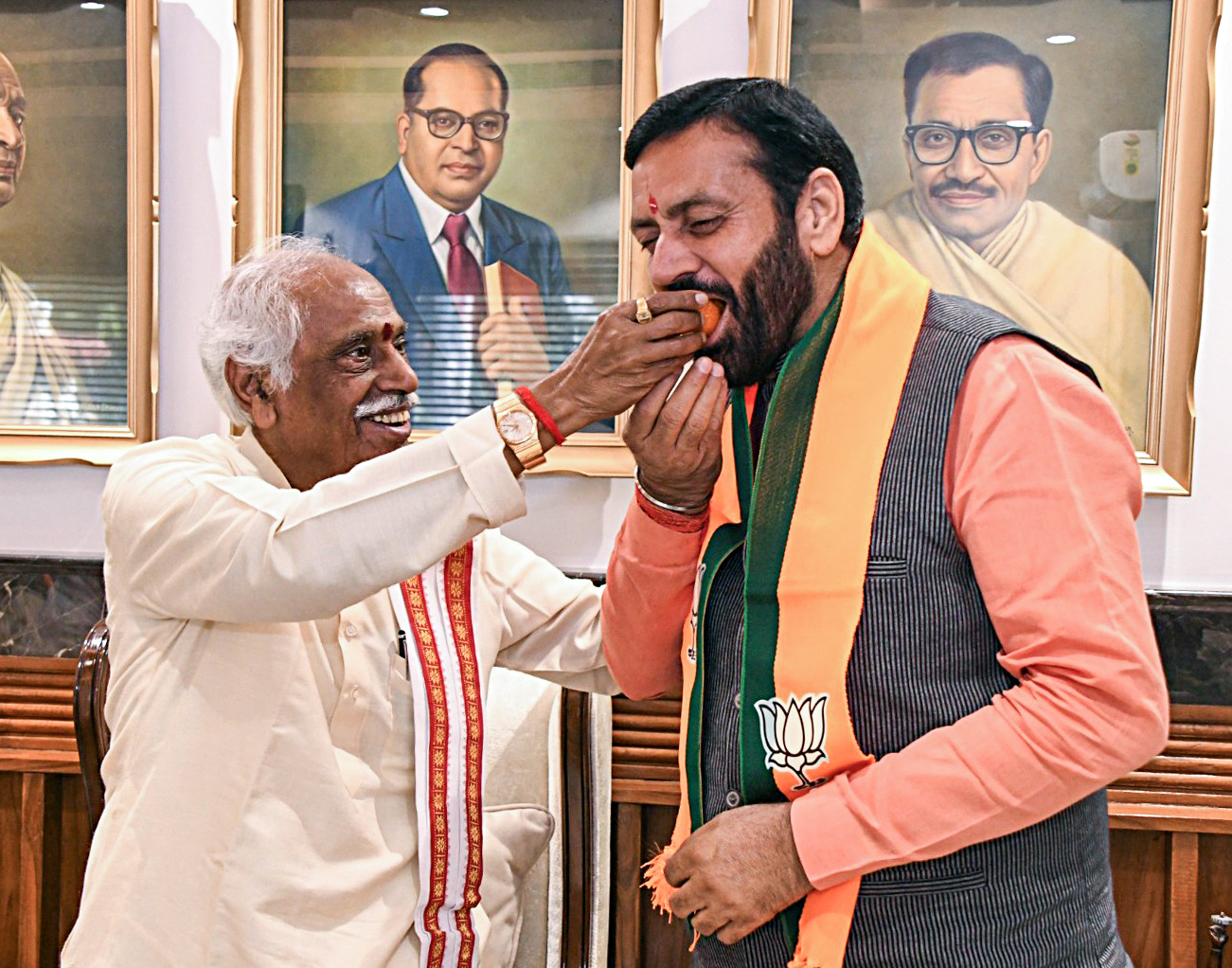 Haryana Governor Bandaru Dattatraya offers sweets to state caretaker CM Nayab Singh Saini as he arrives to submit a letter of support by MLAs to form government, in Chandigarh on Oct 16, 2024..