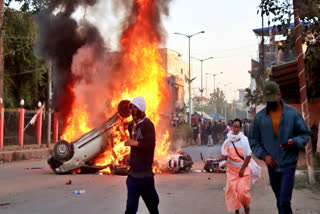 People escape as smoke and flames billow out of vehicles which were set on fire in Imphal.