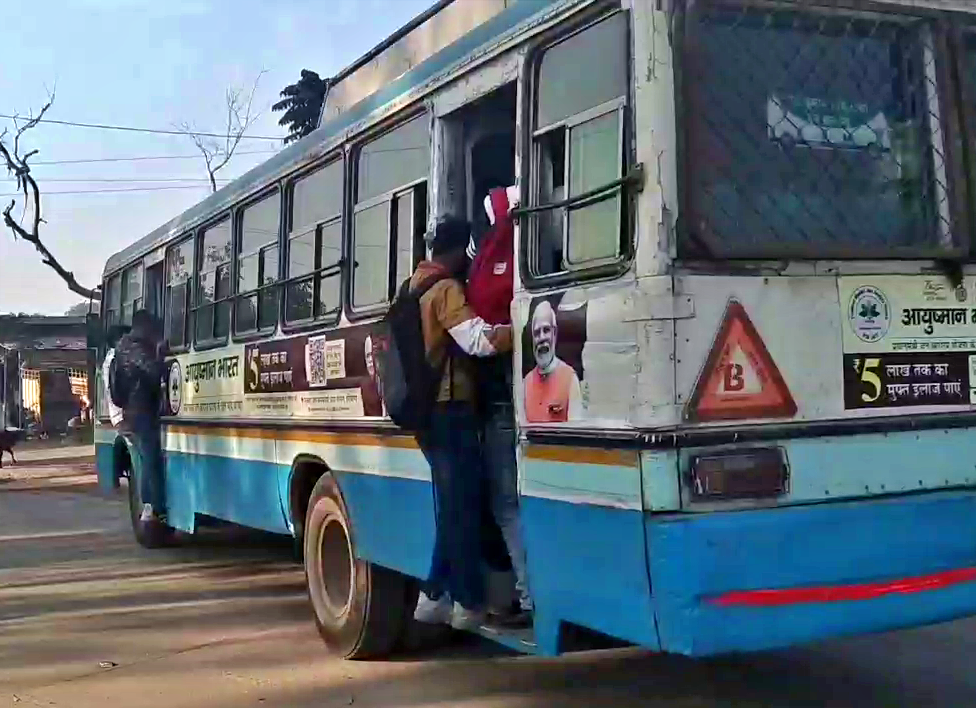 Students traveling by hanging on bus doors