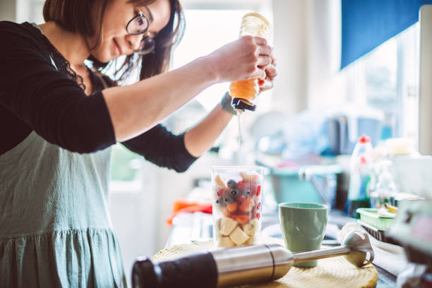 Young pretty woman making fruit smoothie at home