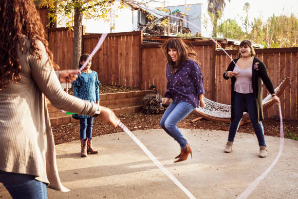 Laughing woman performing double dutch jump rope in backyard