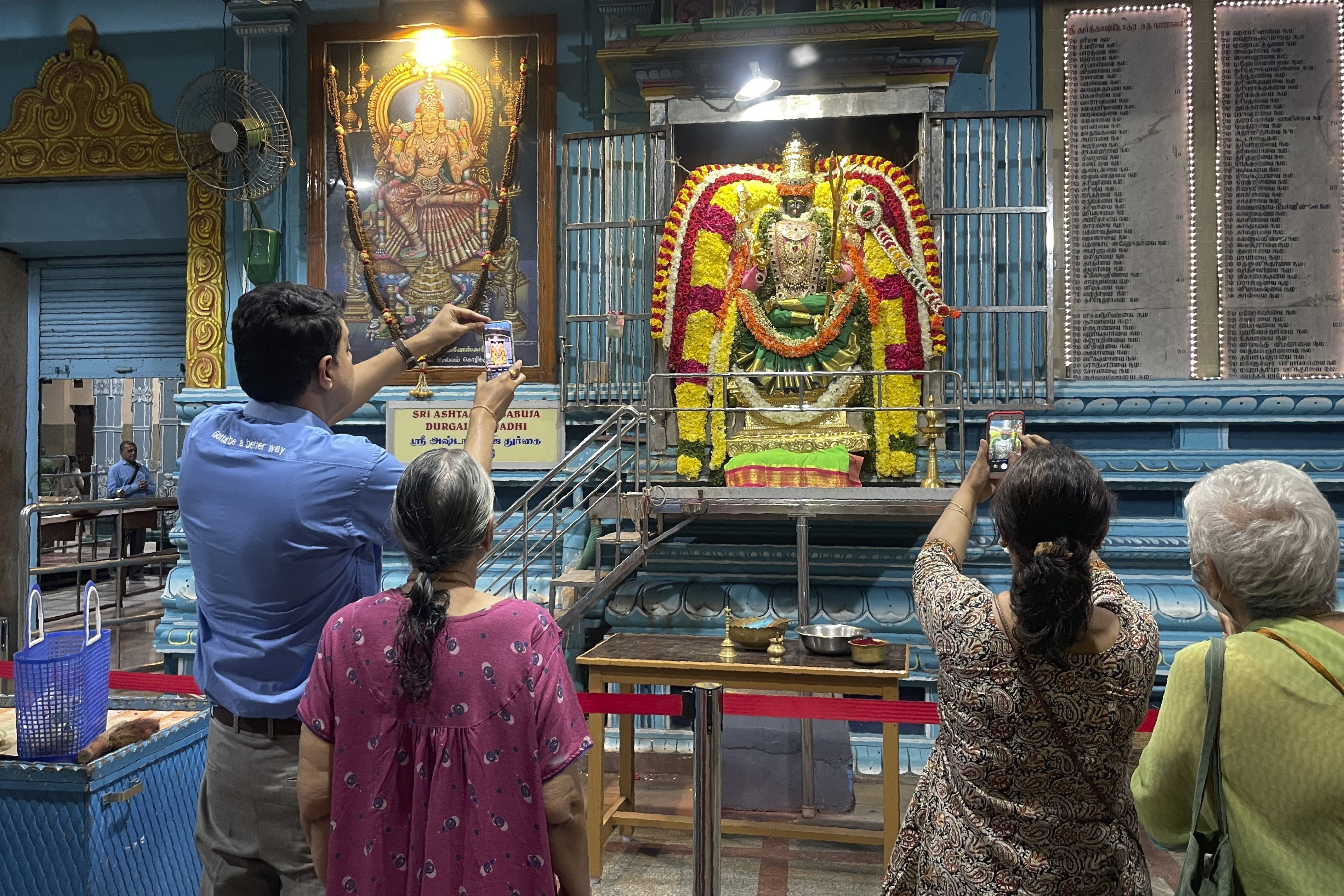 Visitors to the Anantha Padmanabha Swamy Temple in Chennai, India, take photos of the fully decorated idol of the goddess Durga on Nov. 29, 2022. S. Goutham, who spent nearly three hours decorating the idol, is a fifth-generation practitioner of this millennia-old spiritual art of decorating temple deities. (AP Photo)