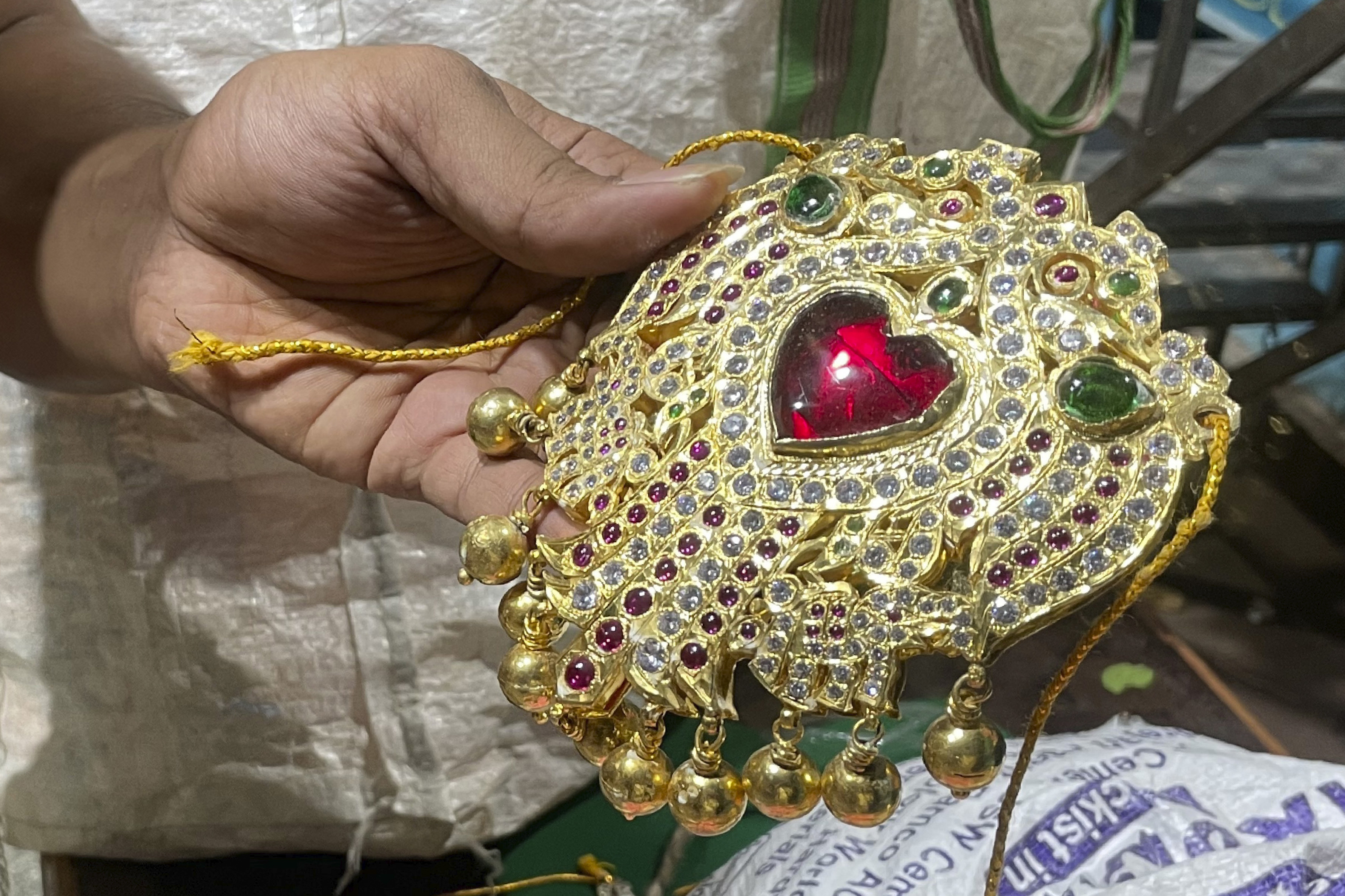 Deity decorator S. Goutham holds a specially crafted piece of jewelry that would adorn the chest of the goddess Durga at the Anantha Padmanabha Swamy Temple in Chennai, India, on Nov. 29, 2022. He says the jewels and weapons on a deity tell a story and give each decoration its unique personality and character. (AP Photo)