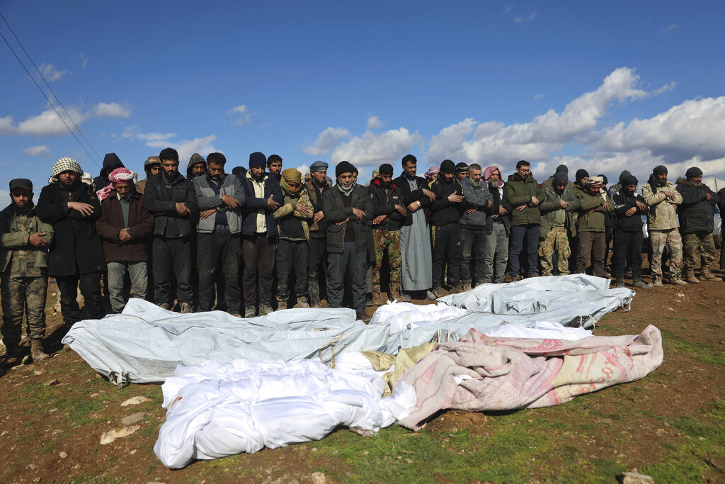 Mourners pray over coffins of family members who died in a devastating earthquake that rocked Syria and Turkey at a cemetery in the town of Jinderis, Aleppo province, Syria, on Tuesday