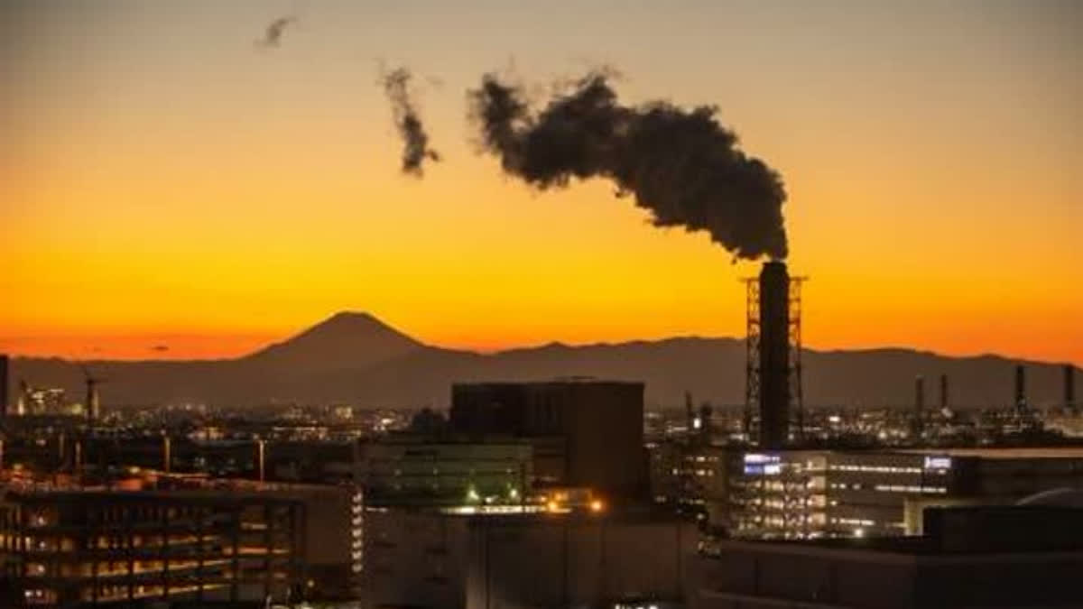 A chimney is seen at the Keihin Industrial Zone as Mount Fuji (background L), Japan's highest mountain at 3,776 meters (12,388 feet), looms in the background as viewed from the observation deck of Kawasaki Marien in Kawasaki on January 24, 2022.