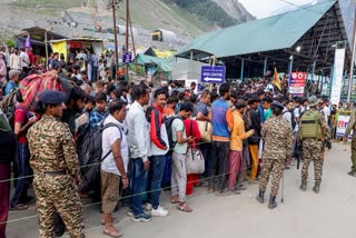 Security personnel keep vigil as the pilgrims of the Amarnath Yatra stand in queues during their pilgrimage to the shrine, at the Baltal base camp in Ganderbal on Wednesday.