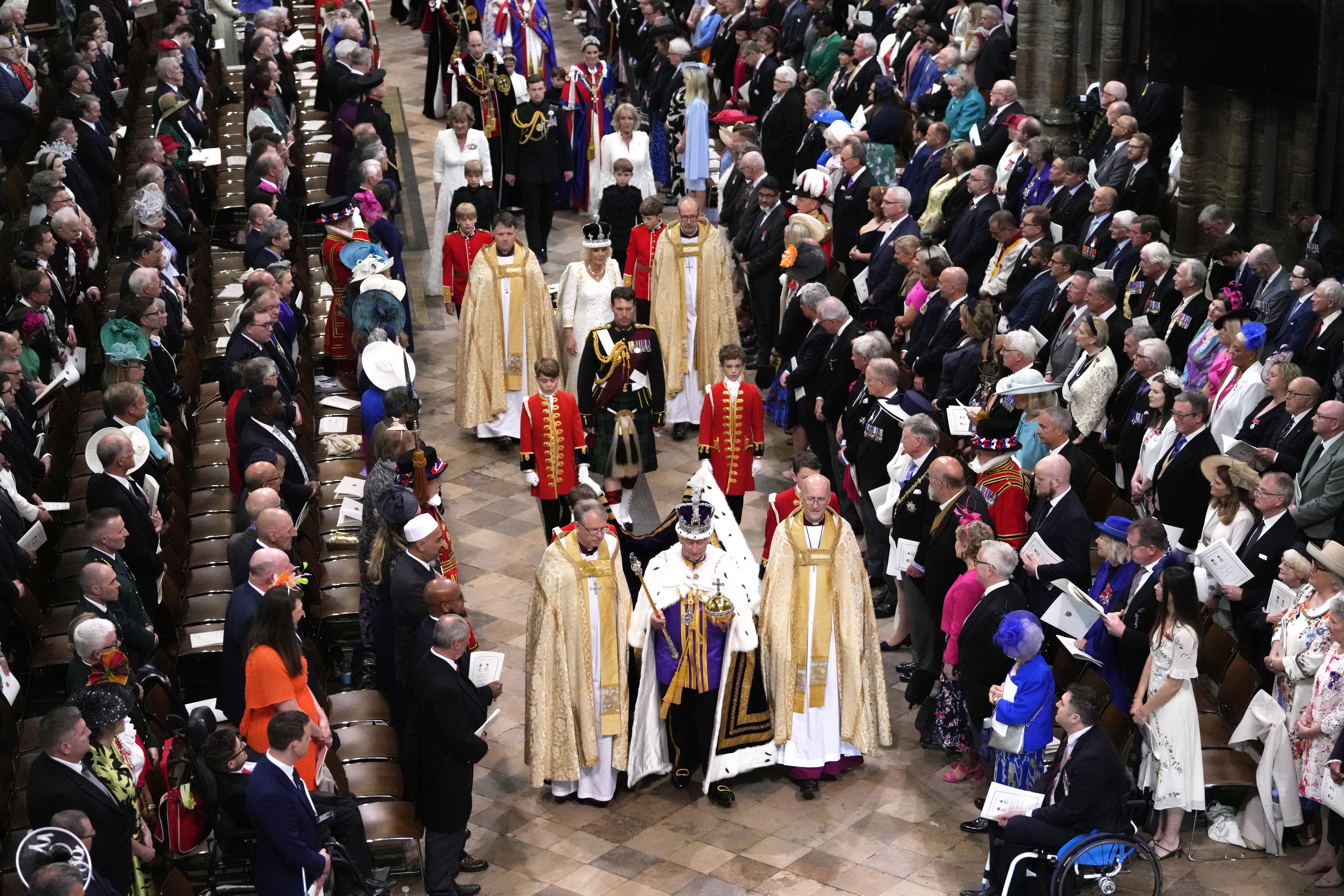 King Charles III, front center, and Queen Camilla, middle center, walk in the Coronation Procession at Westminster Abbey in London