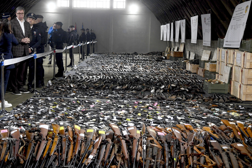 In this photo provided by the Serbian Presidential Press Service, Serbian President Aleksandar Vucic, left, inspects weapons collected as part of an amnesty near the city of Smederevo, Serbia, Sunday, May 14, 2023. Serbian authorities on Sunday displayed some of around 13,500 weapons they say have been collected since last week's mass shootings, including automatic weapons, hand bombs and anti-tank grenades.