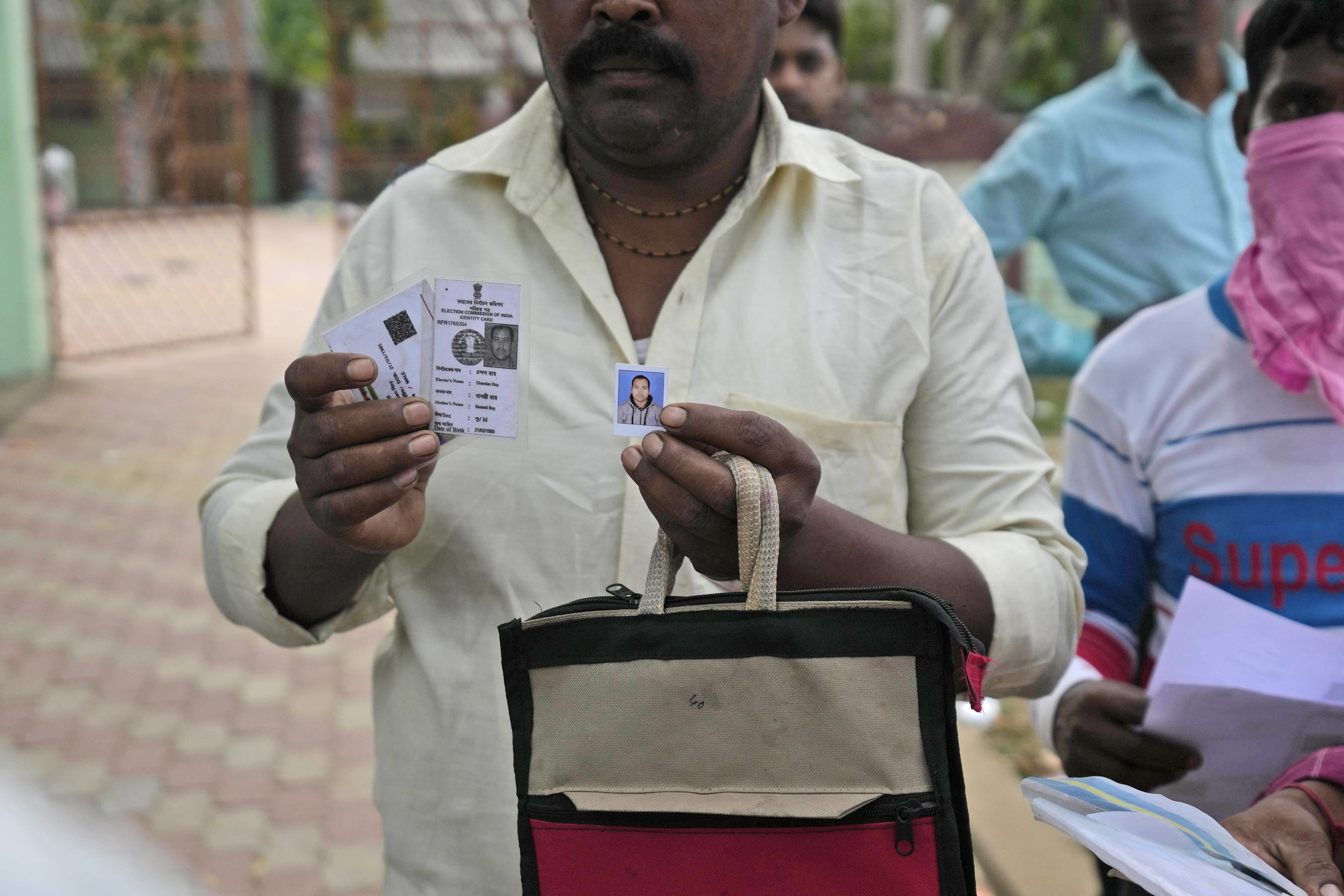 A person shows photo of his relative who was traveling in the train that derailed while looking for him at the site of the accident, in Balasore district (Photo: AP)