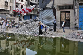 Palestinians displaced by the Israeli air and ground offensive on the Gaza Strip walk next a dark streak of sewage flowing into the streets of the southern town of Khan Younis, Gaza Strip, Thursday, July 4, 2024.