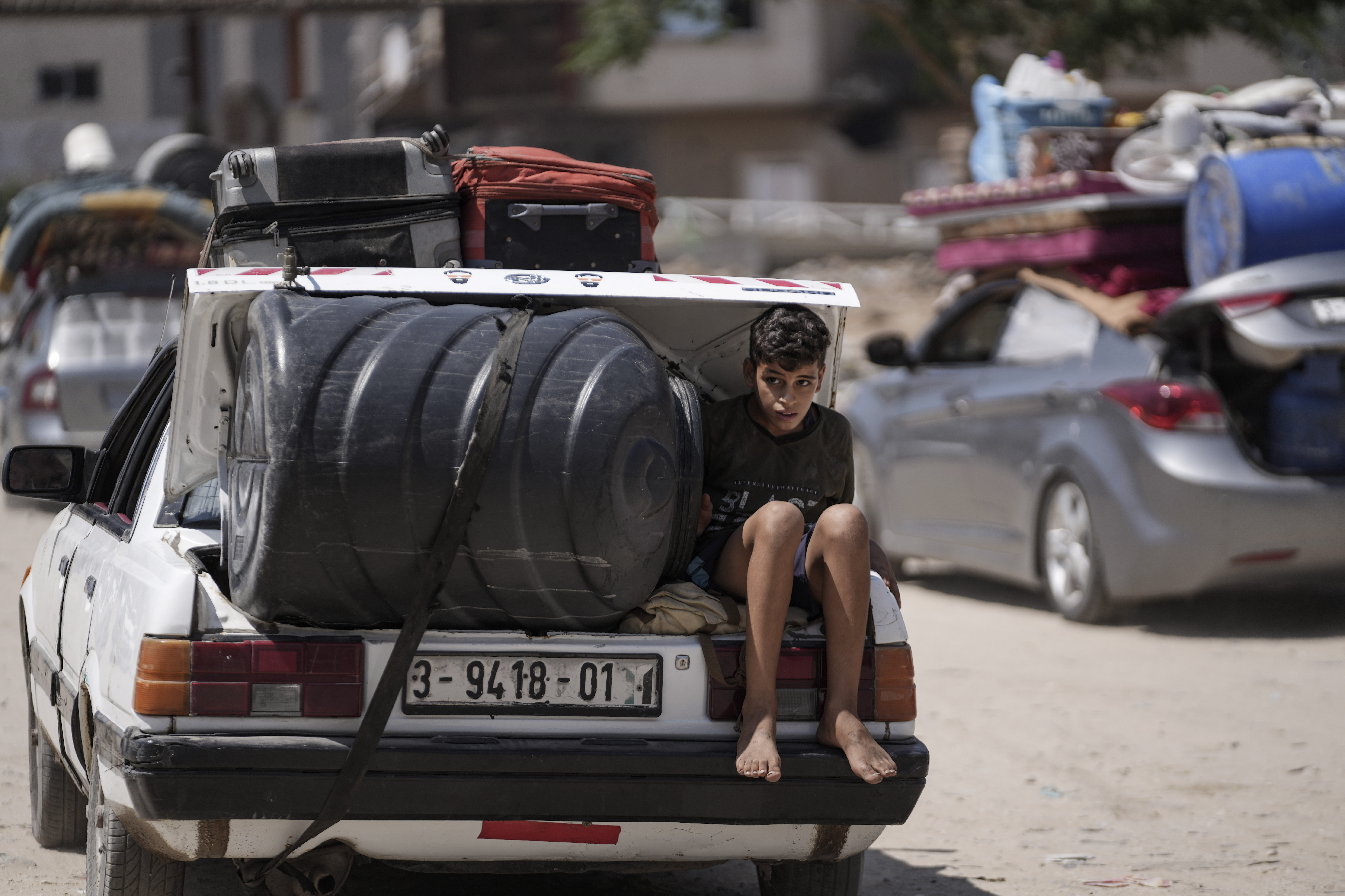 A Palestinian child rides in the trunk of a car as he evacuates Maghazi refugee camp in the central Gaza Strip, as part of a mass evacuation ordered by the Israeli military ahead of an operation, Saturday, Aug. 17, 2024.