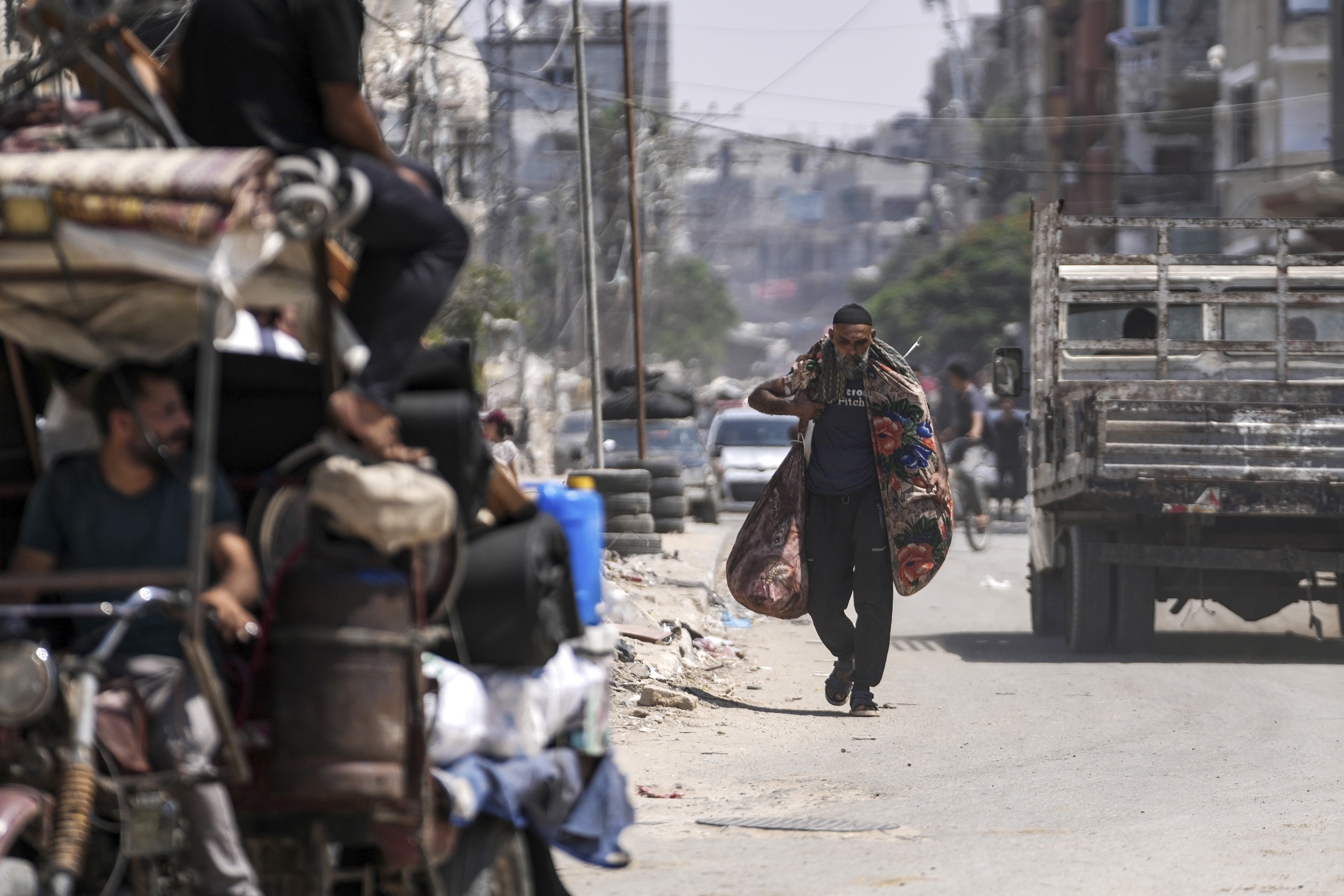 A Palestinian carries his belongings as he evacuates Maghazi refugee camp in the central Gaza Strip, as part of a mass evacuation ordered by the Israeli military ahead of an operation, Saturday, Aug. 17, 2024.