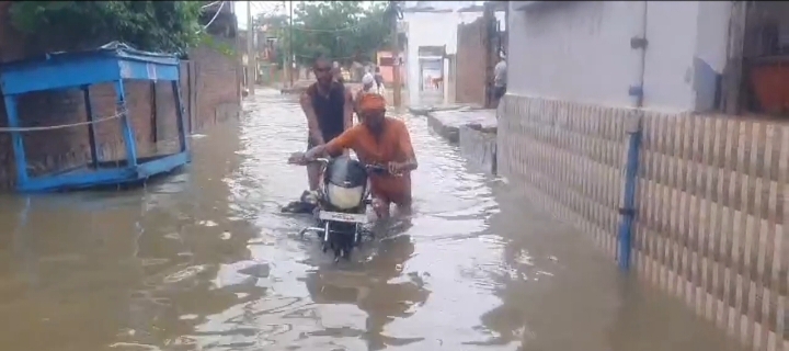 जलभराव के बाद बाइक लेकर जाते लोग