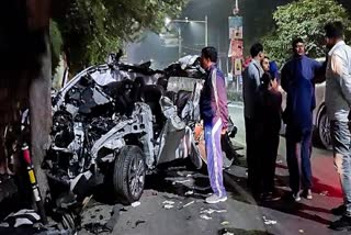 People gather around the car that got mangled after it got hit by a container, in Dehradun due to overspeeding and brake failure