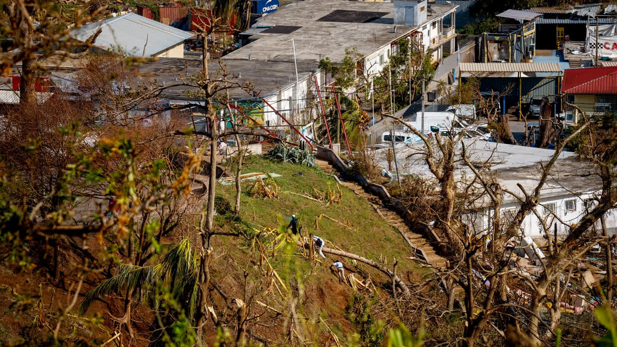 People climb a hill in the city of Mamoudzou, on the French Indian Ocean territory of Mayotte, on December 18, 2024, after the cyclone Chido hit the archipelago.