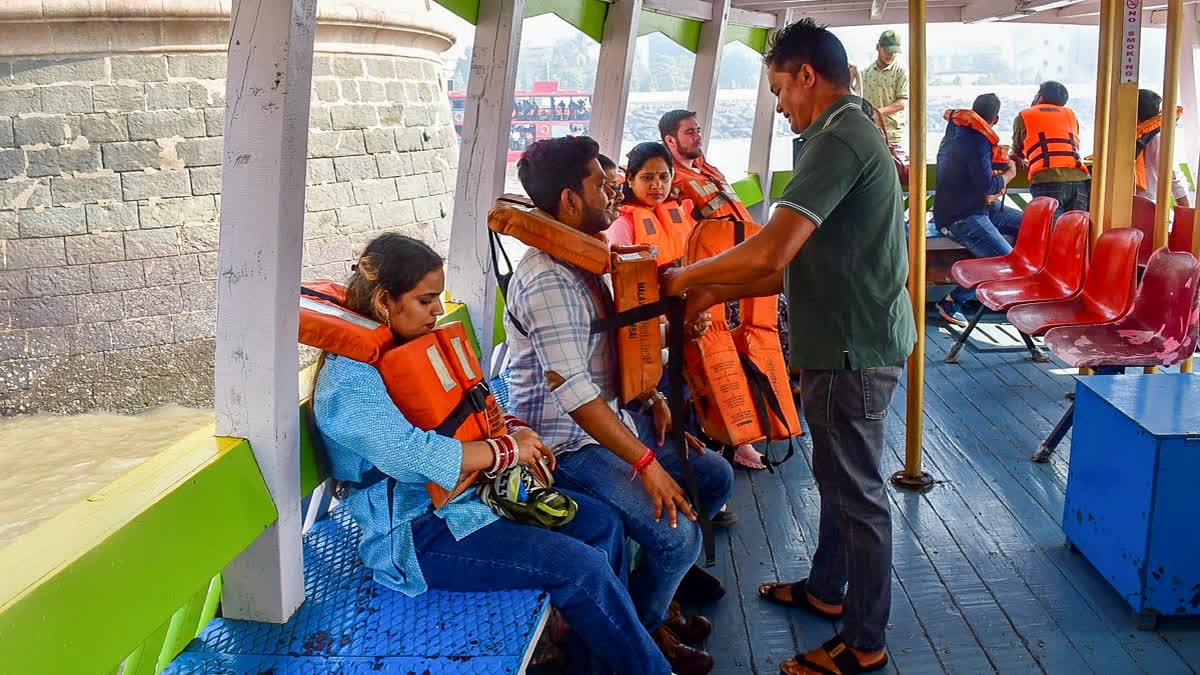 A passenger gets assisted to wear a life jacket following the distribution of life jackets to passengers after a ferry capsized off the Mumbai coast when a Navy craft crashed into it on Wednesday, in Mumbai, Thursday, Dec. 19, 2024.