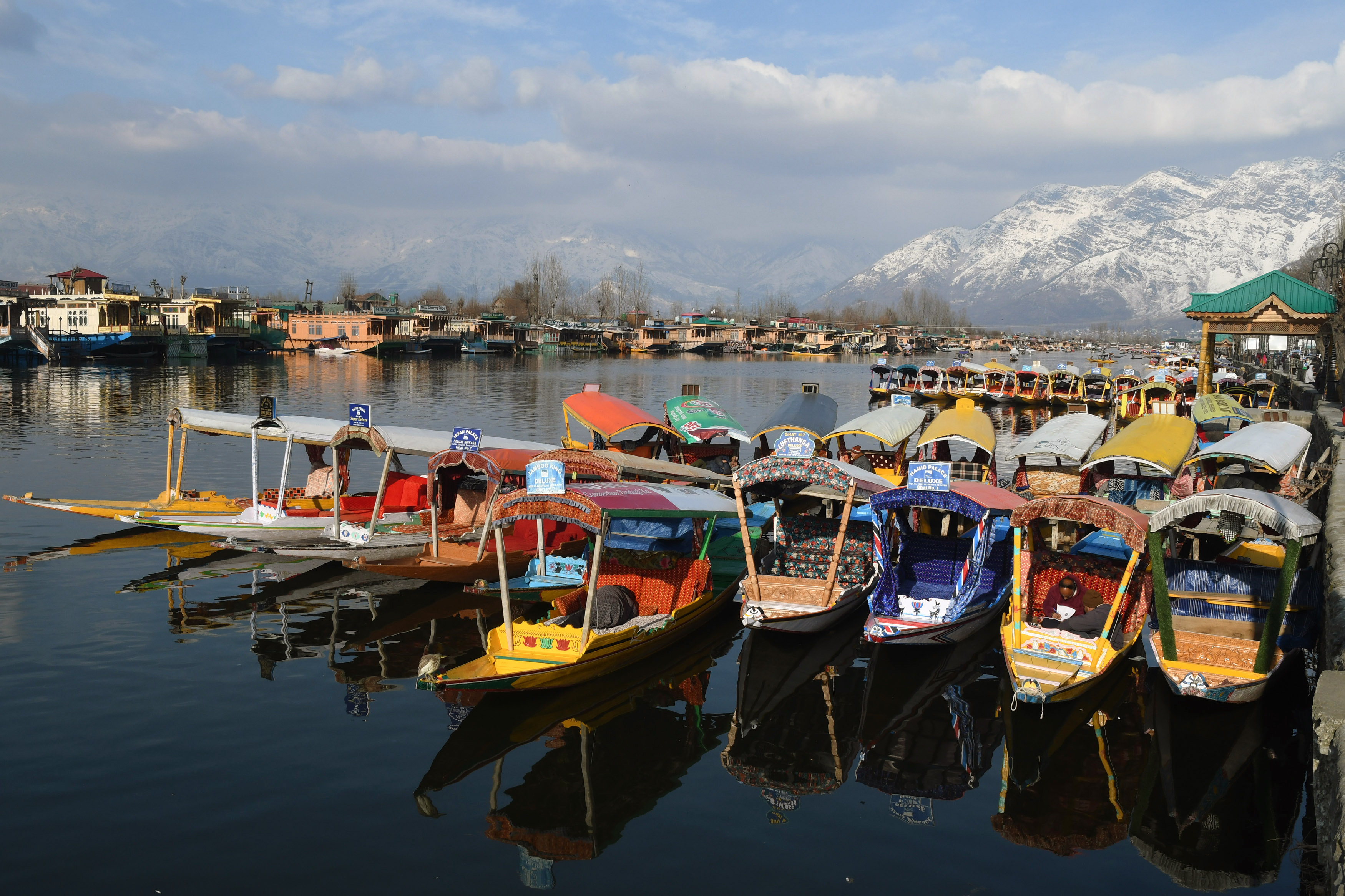 A view of Shikaras anchored at the Dal Lake against the backdrop of snow-capped mountains, in Srinagar