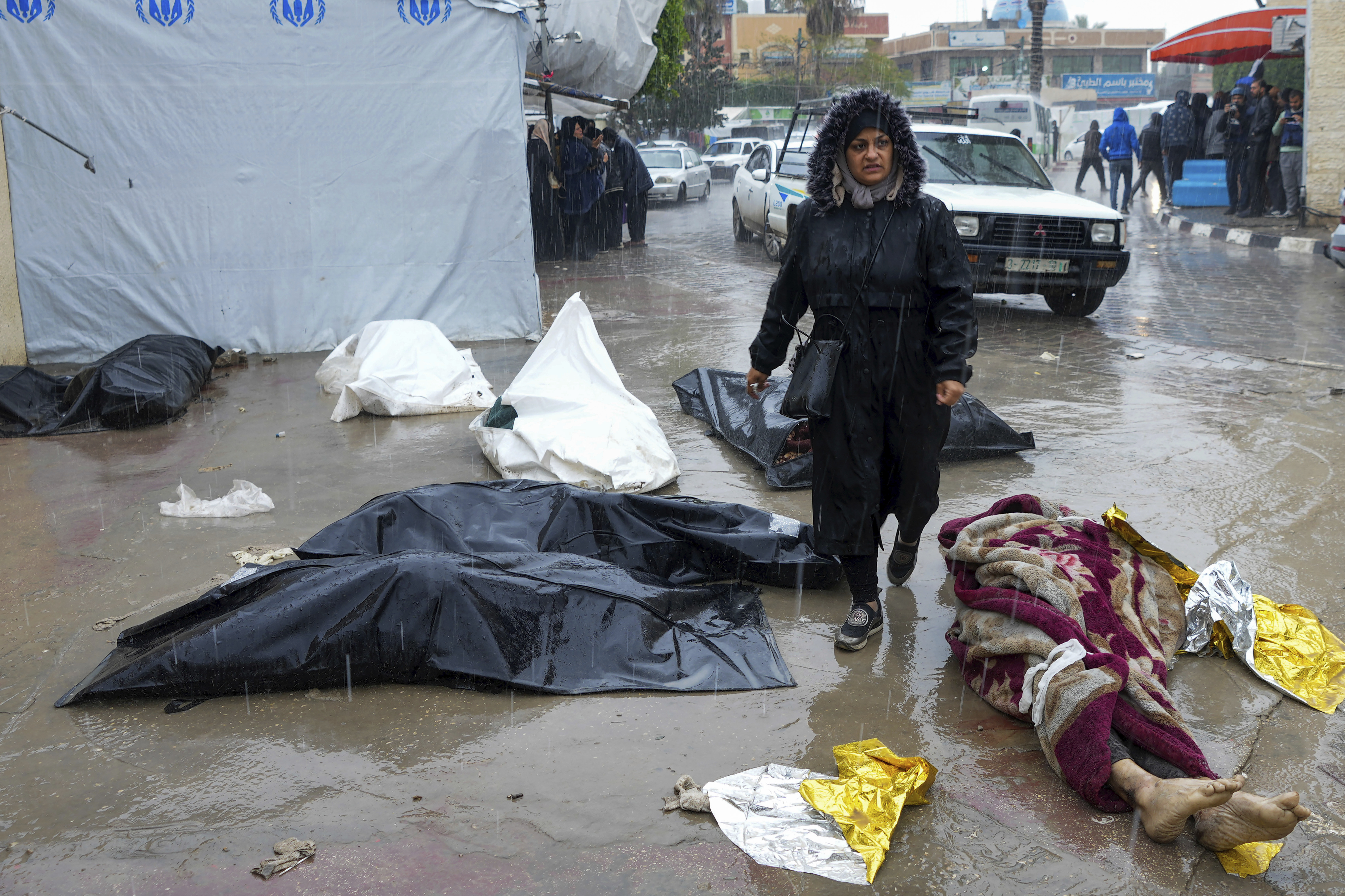 غزہ میں لاشوں کے بیچ سے گزرتی ایک فلسطینی خاتون۔۔۔( Photo: AP)