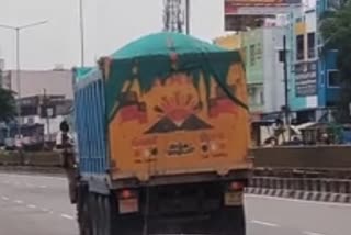 லாரியின் கதவில் தொங்கியபடி செல்லும் போலீஸ்காரர்