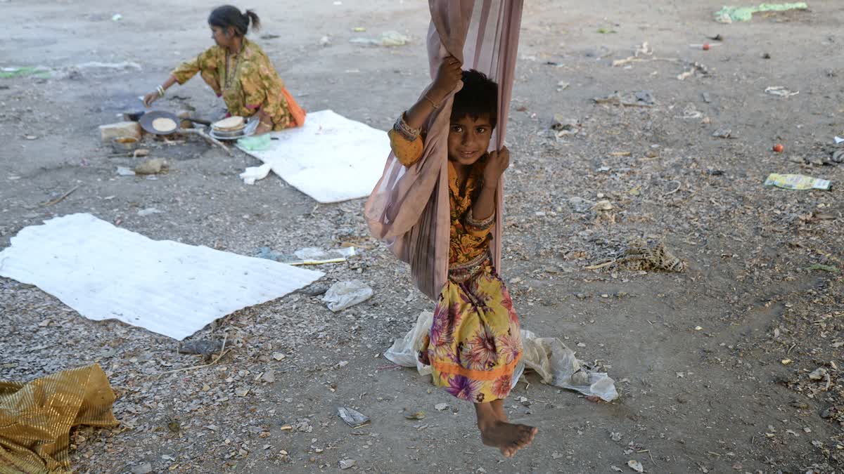 A homeless child rides a DIY swing as her mother prepares food, at a roadside, in Jalandhar on Sunday.(Representational picture)